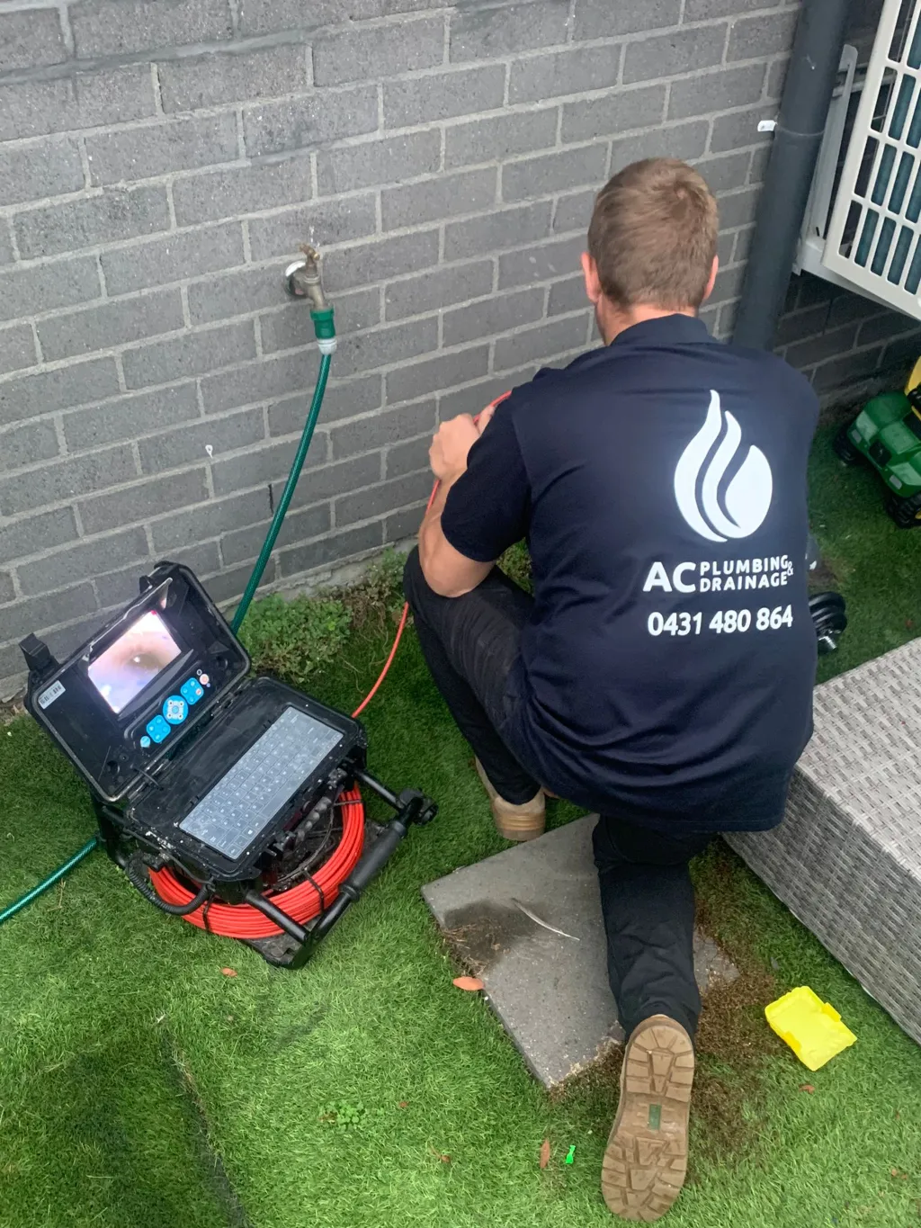 Drain camera reel and monitor set up beside a brick wall on a job.