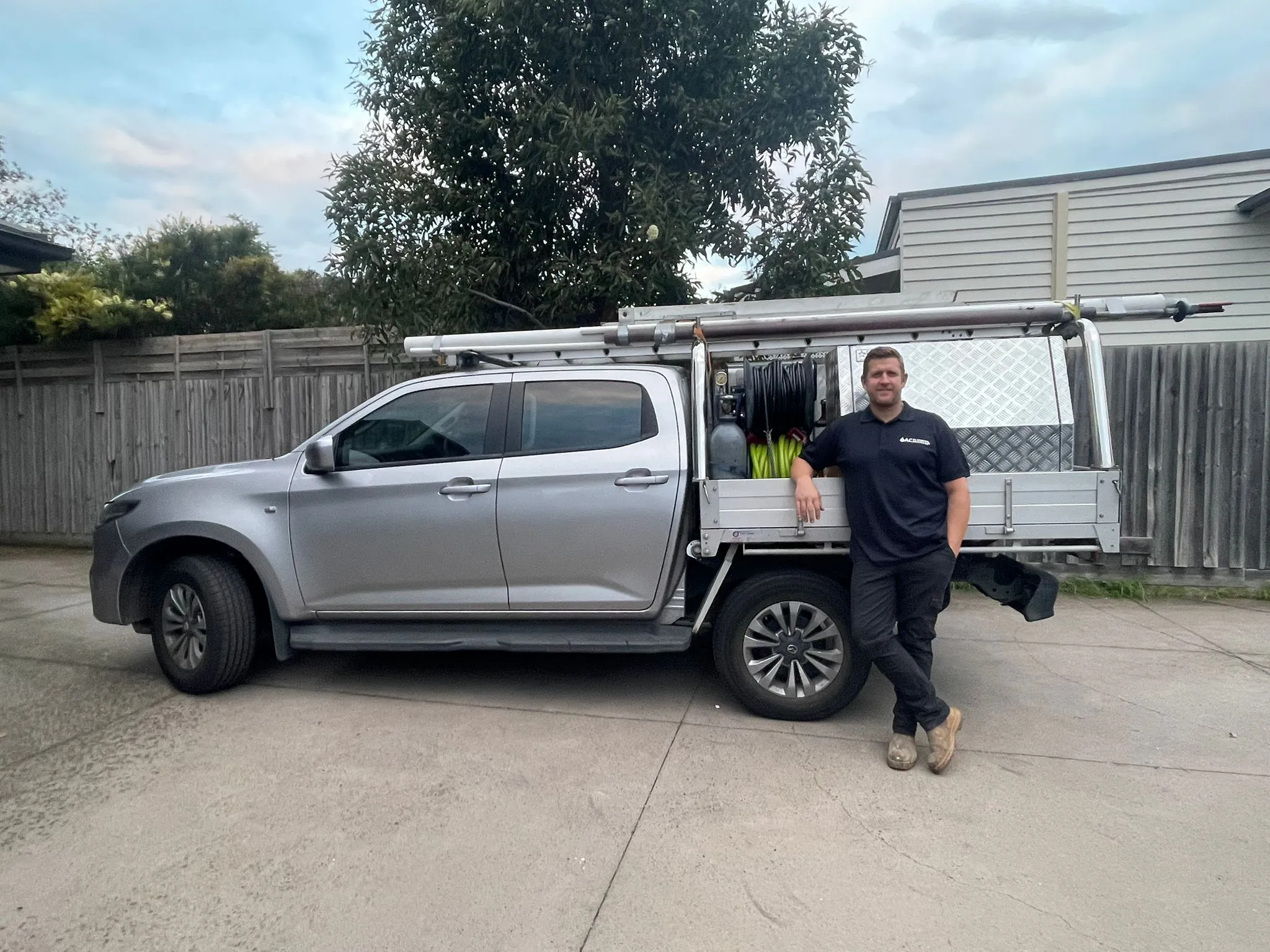 A second AC Plumbing team member beside the silver dual-cab ute.